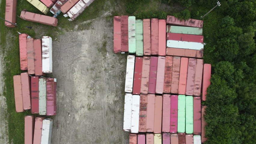 Stacked colorful shipping containers in a forest, aerial view
