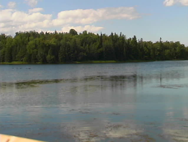 Canoing man on a quite peaceful lake in ontario goes by camera.