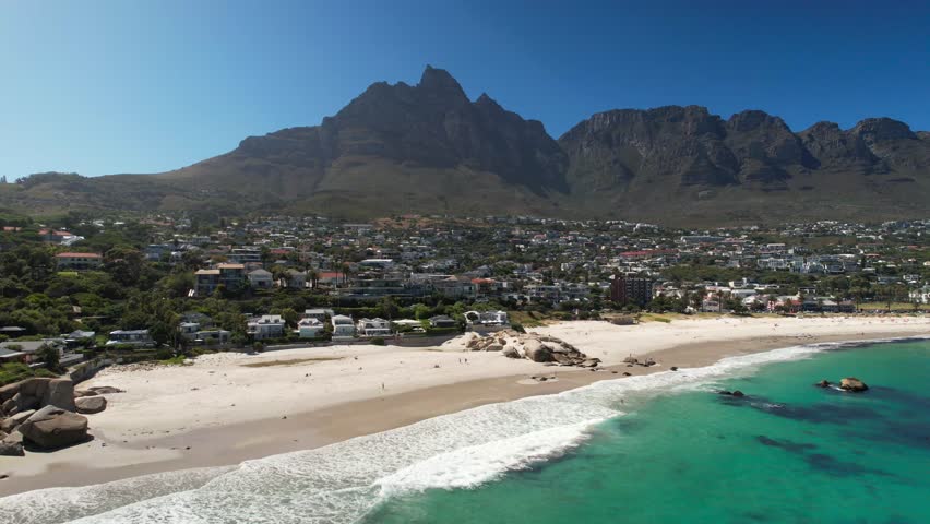 Noble African neighborhood with waterfront villas in Cape Town, South Africa. Sunny day with blue sky and clear bay water. Aerial wide shot.