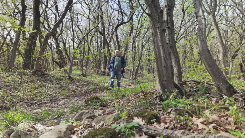 Senior man listens to woodland nature sounds during springtime walk