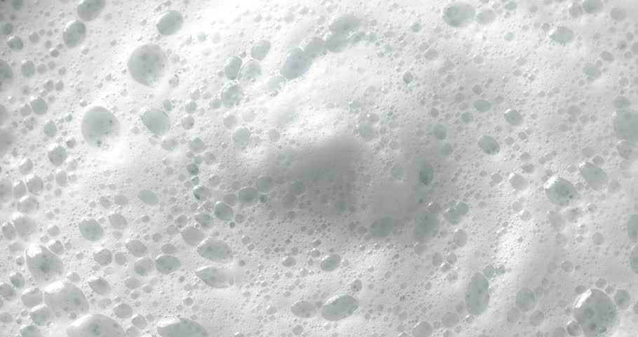 Foam bubbles background. Moving Soap foam popping bubble. Close-up footage on the rotating table.