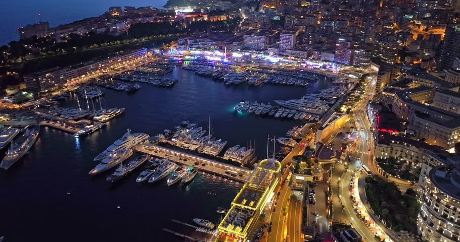 Aerial establishing shot of illuminated city buildings. Aerial view of illuminated skyscraper in residential city at night, Monte Carlo, Monaco