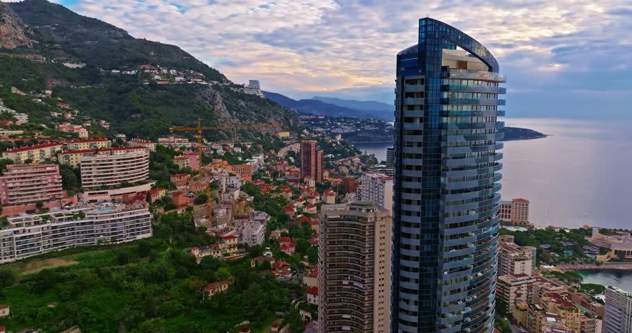 Aerial view of the city center of Monaco. Establishing shot showcases luxury yachts moored in Monaco Bay, the Palais Princier de Monaco, and luxury apartment buildings of Monte Carlo