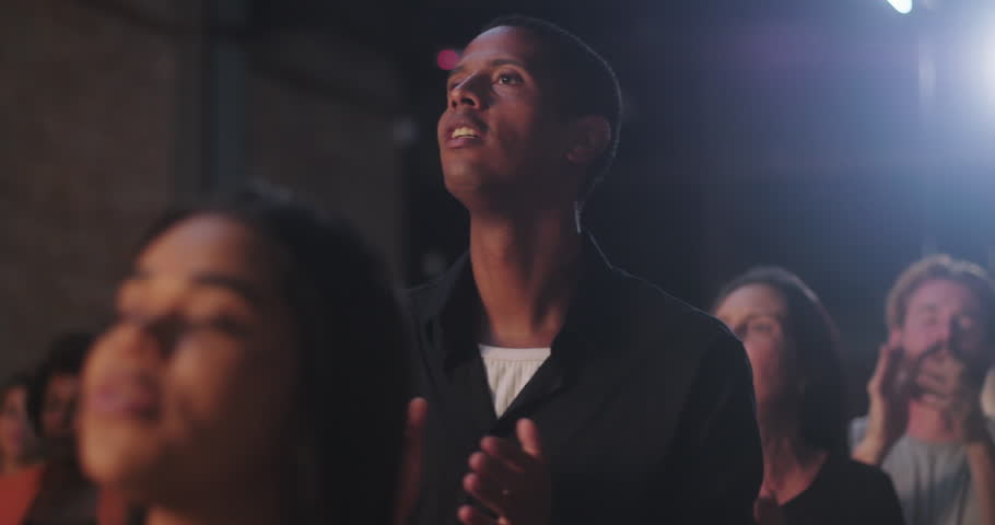 Man clapping in evangelical church worship, Afro-descendant male with joyful expression, black shirt, community celebration of faith, spiritual devotion and praise