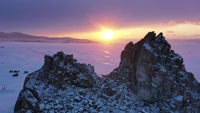 Aerial view of Shaman rock at sunset, one of sacred place in frozen lake Baikal in winter season of Siberia, Russia, 4k