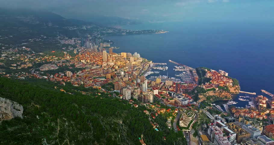 Aerial view of the city center of Monaco. Establishing shot showcases luxury yachts moored in Monaco Bay, the Palais Princier de Monaco, and luxury apartment buildings of Monte Carlo