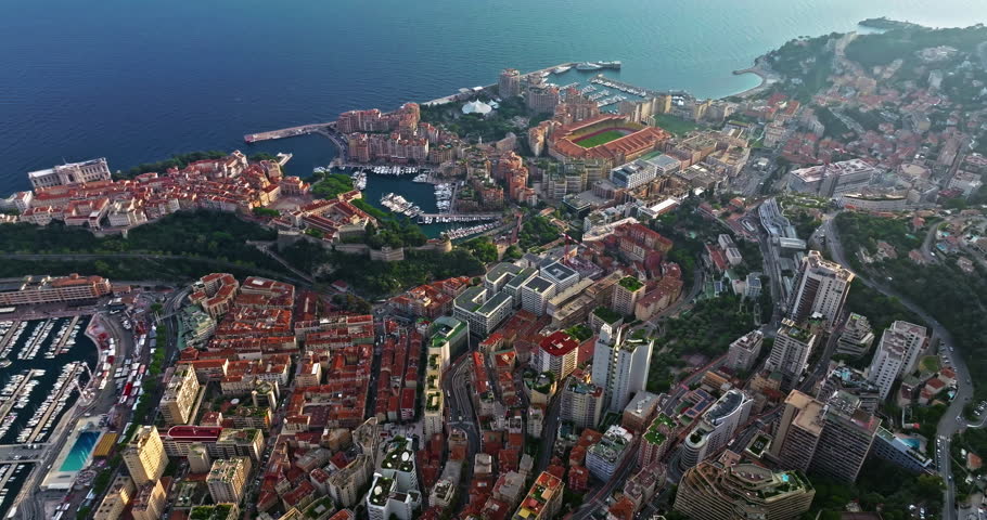 Aerial view of the city center of Monaco. Establishing shot showcases luxury yachts moored in Monaco Bay, the Palais Princier de Monaco, and luxury apartment buildings of Monte Carlo