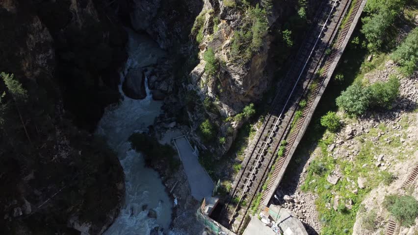 Aerial view of a funicular railway track crossing a narrow valley with a river