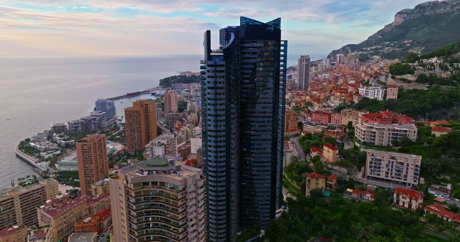 Aerial view of the city center of Monaco. Establishing shot showcases luxury yachts moored in Monaco Bay, the Palais Princier de Monaco, and luxury apartment buildings of Monte Carlo