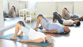 Elderly woman performs glute bridge with softball in knees. High quality 4k footage - Powered by Shutterstock - Get 15% off with code: PIKWIZARD15