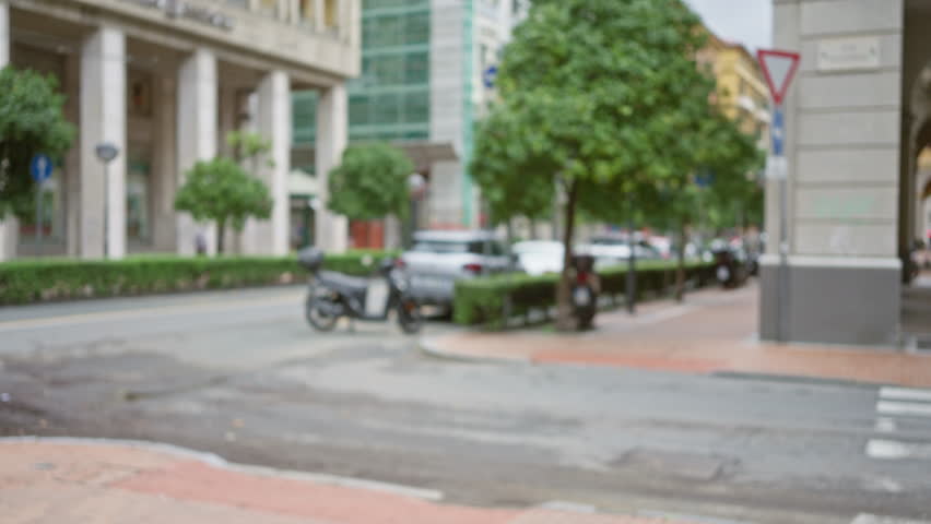 Blurred urban street scene in la spezia italy featuring out of focus trees buildings and parked motorcycles.