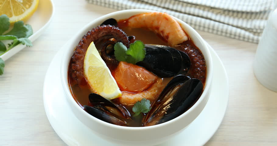 Woman eating delicious seafood soup at table, closeup
