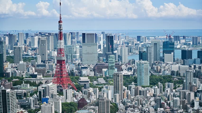 Panoramic aerial view of Tokyo Tower with city skyline of financial skyscraper buildings and see water in the background.