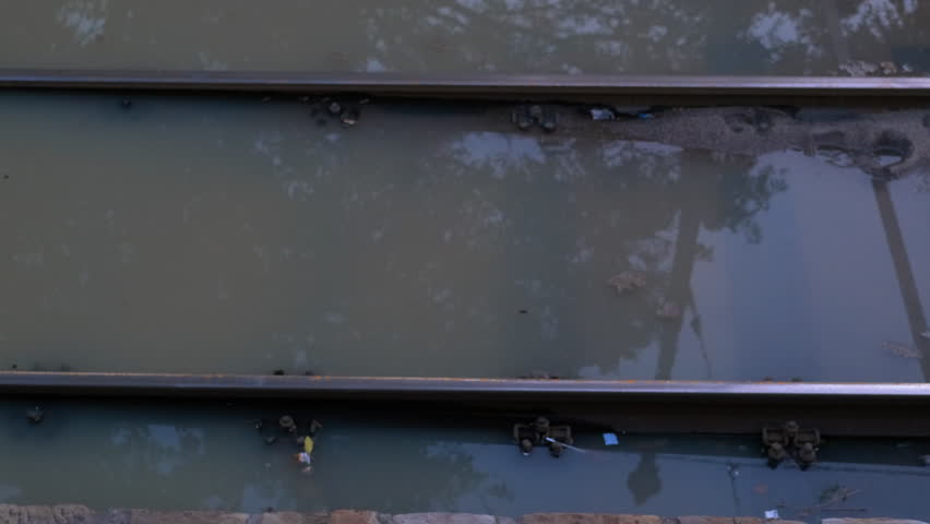 Flooding on the railway. Rainwater flooding over railway tracks in a city, affecting infrastructure and causing transportation disruptions as storm reflects on water surface