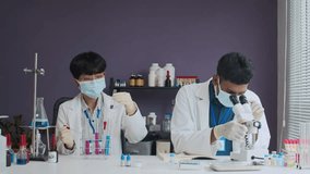 Biracial scientists wearing white coat and protective mask working with samples together in lap - Powered by Shutterstock - Get 15% off with code: PIKWIZARD15
