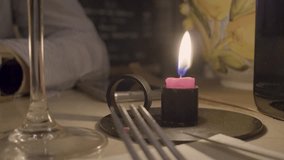 A close-up shot of a pink candle burning brightly next to some utensils and a glass - Powered by Shutterstock - Get 15% off with code: PIKWIZARD15