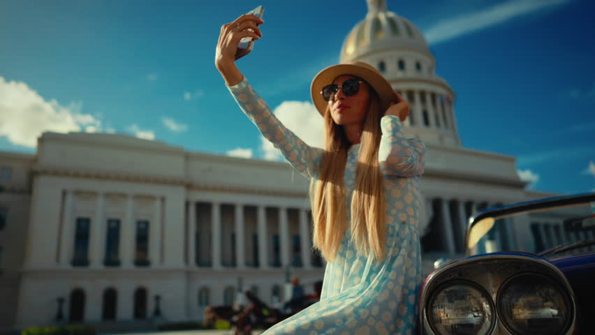 Happy woman tourist taking selfie against historical landmarks in old town. Summer vacation in beautiful country with unique culture, female travel blogger smiling broadly to camera, sunny summer day