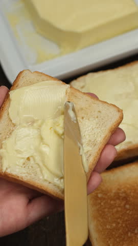 Spreading soft butter on a piece of toast bread. Making breakfast toast