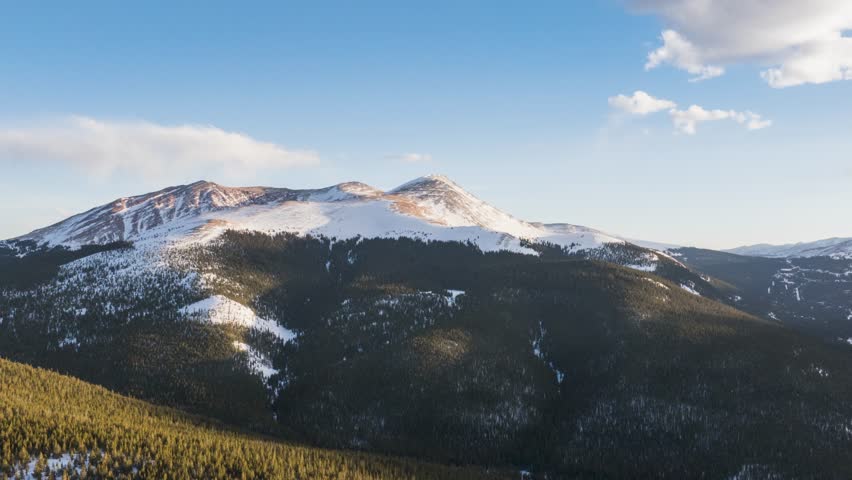 Aerial pan shot of snow topped mountain in Breckenridge, Colorado of USA against blue sky. TImelapse view.