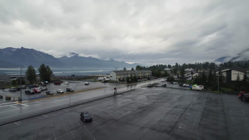 Parking cars at parking area in Seward Town during cloudy day. Aerial flyover shot. Rainy day in american town of Alaska. ROw of houses with River bay view.