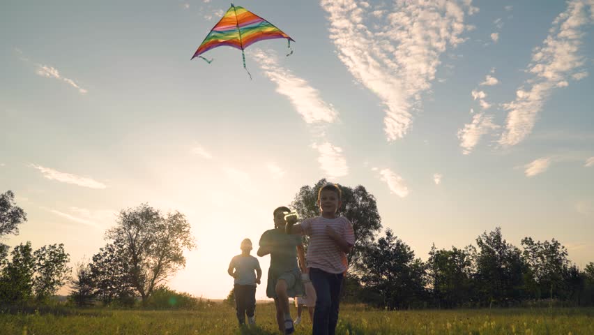 Kids boy girl flying toy kite high in sky, childish emotions. Childhood dream to fly concept. Children play in park with kite. People play with kite, summer meadow. Happy family run active lifestyle