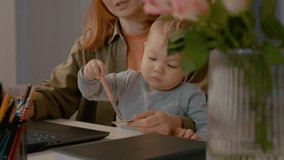 Young mother manages her home office by holding her baby in one hand and using her bank card to shop online. She balances family life with technology seamlessly. - Powered by Shutterstock - Get 15% off with code: PIKWIZARD15