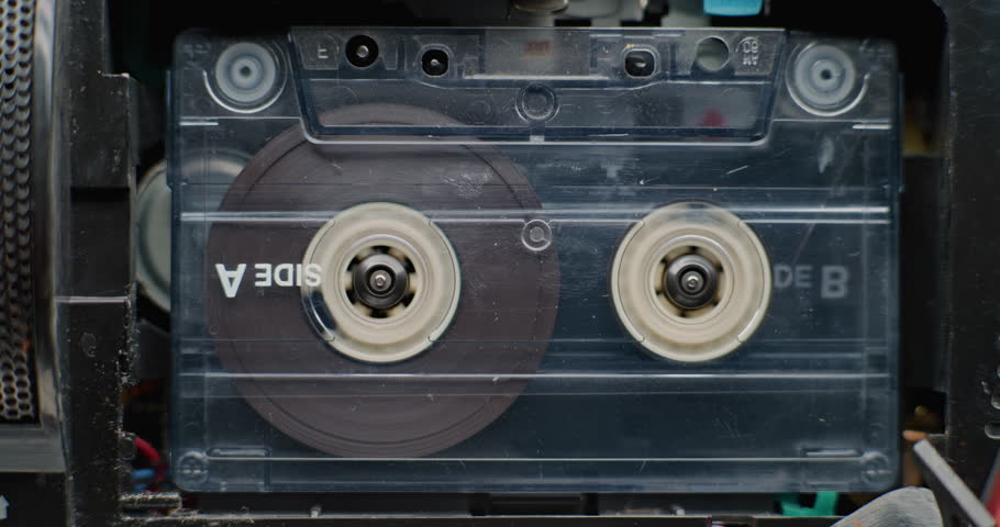 Macro Close Up of Retro Audio Cassette Tape Playing 70s Mixtape Sound Inside Tape Deck. Playback of Old Music Using Hi-Fi Vintage Sound System with Nostalgic Atmosphere. Reel-to-Reel Tape Recorder.