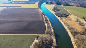 Aerial view of a winding river cutting through vast agricultural fields, showcasing the contrast between plowed farmland and lush greenery under a clear blue sky - Powered by Shutterstock - Get 15% off with code: PIKWIZARD15
