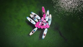 Aerial top-down view of a group practicing yoga on a floating SUP island in the middle of a serene lake. Calm water reflects the sky, creating a peaceful, harmonious scene. - Powered by Shutterstock - Get 15% off with code: PIKWIZARD15