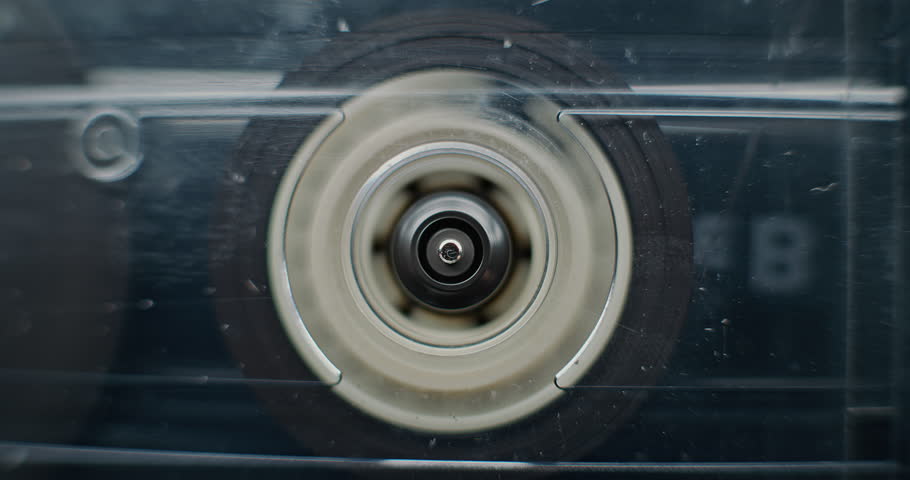 Macro Close Up of Magnetic Tape Reel on Vintage Audio Cassette Spinning, Playing Music or Analog Sound. Playback of Mixtapes Using Old Fashioned Audio Equipment with Retro Vibe. Reel Tape Recorder.