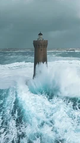 Aerial view of Jument lighthouse during storm and huge waves crashing against it