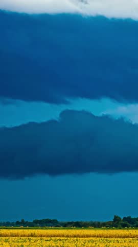 Timelapse of dramatic sky over farmland with machine moving through yellow field