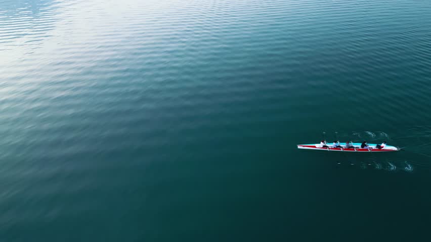 Sport Canoe with a team of four people rowing on tranquil water, Aerial view.