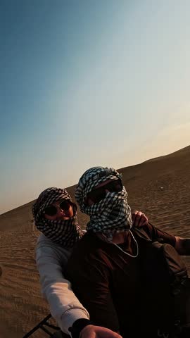 Tourists riding quad bike in desert at sunset