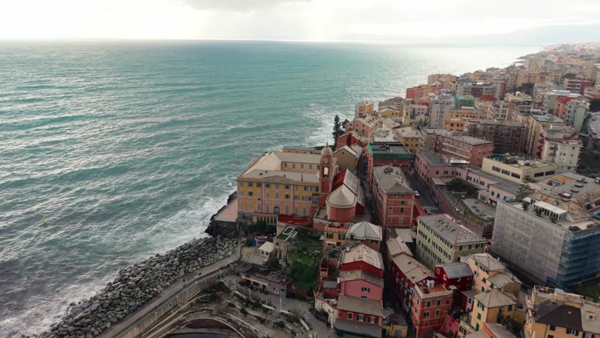 Scenic aerial shot of Genoa, Italy, overlooking colorful coastal buildings and rough seas
