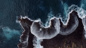 Aerial view of waves crashing against jagged black lava shoreline in Hawaii, creating dramatic white foam patterns in deep blue ocean waters - Powered by Shutterstock - Get 15% off with code: PIKWIZARD15