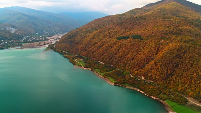 A drone view of the river in the woods. An aerial view of an autumn forest. Winding river among the trees. Turquoise mountain water. Landscape with soft light before sunset. Georgia, Ananuri Mountains