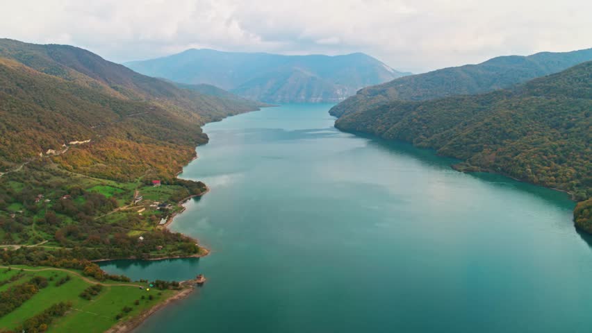 A drone view of the river in the woods. An aerial view of an autumn forest. Winding river among the trees. Turquoise mountain water. Landscape with soft light before sunset. Georgia, Ananuri Mountains
