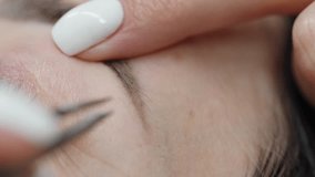 Close-up video of a beautician using tweezers to pluck and shape an eyebrow during a precision grooming or cosmetic treatment session.
 - Powered by Shutterstock - Get 15% off with code: PIKWIZARD15