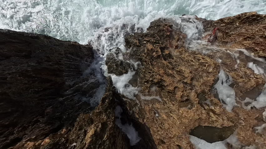 A tiny planet effect distorts a rocky shoreline into a spherical perspective, with the ocean appearing as a dome as waves crash against the jagged formations