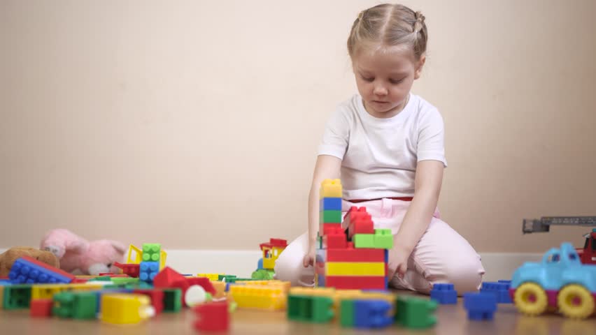 Young girl playing with blocks. Child plays with toy and a constructor. A kindergarten built by a constructor at the development. A little girl experimenting with building blocks lifestyle.