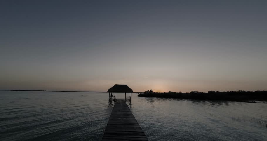 Tranquil scene of a wooden pier leading to a hut at sunrise in bacalar, mexico
