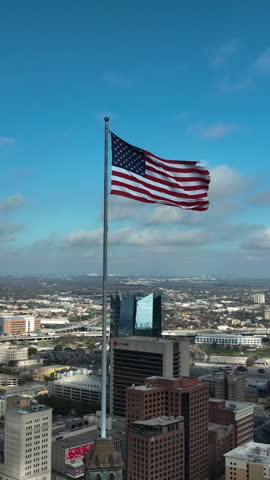 San Antonio , United States - 03 29 2025: Vertical drone shot circling a US flag on top of a building, in sunny San Antonio