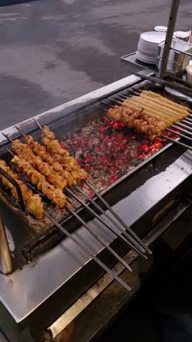 In Delhi, a street food vendor grills chicken skewers by carefully placing them
