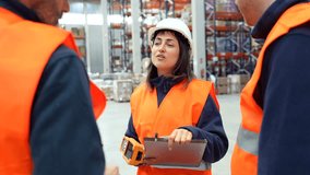 Professional warehouse supervisor wearing safety gear collaboratively discussing logistics and operational details with team members during indoor workplace meeting - Powered by Shutterstock - Get 15% off with code: PIKWIZARD15