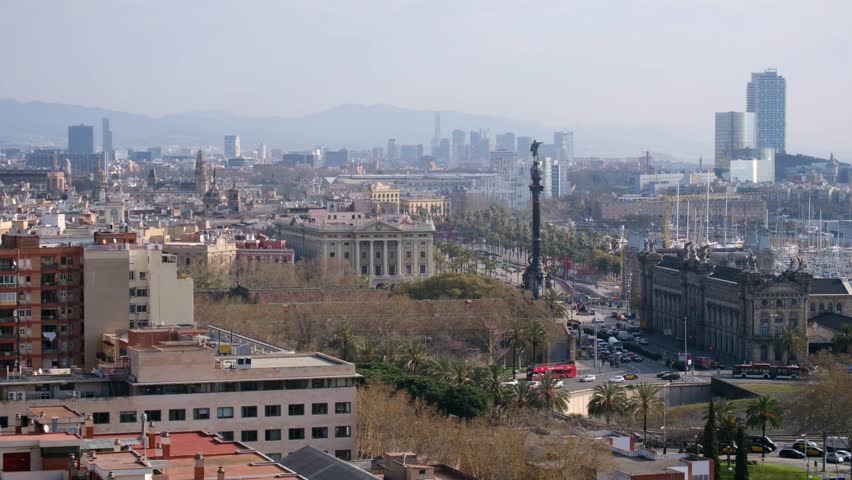 Hazy Barcelona cityscape panorama featuring the prominent landmark and distant mountains.	