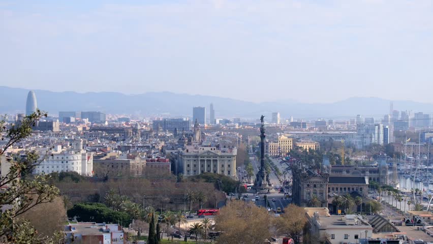 Hazy Barcelona cityscape panorama featuring the prominent landmark and distant mountains.	