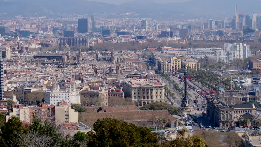 Hazy Barcelona cityscape panorama featuring the prominent landmark and distant mountains.	