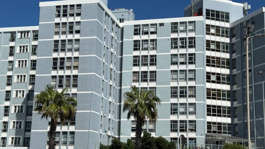 A grey apartment building with palm trees. Sea Point, Cape Town.
