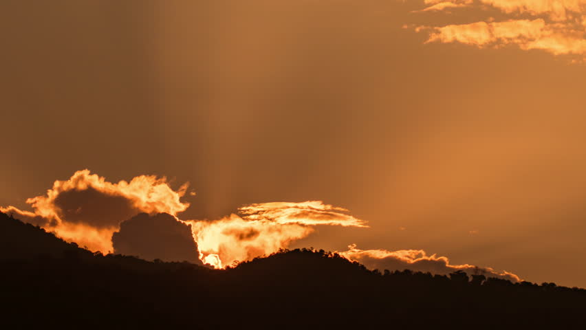 Timelapse of dramatic sunrise with orange sky in a cloudy day.